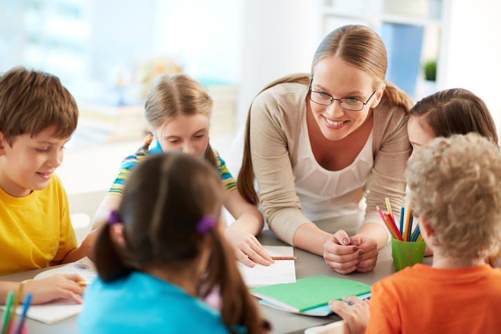 Lächelnde Pädagogin mit Kindern am Tisch