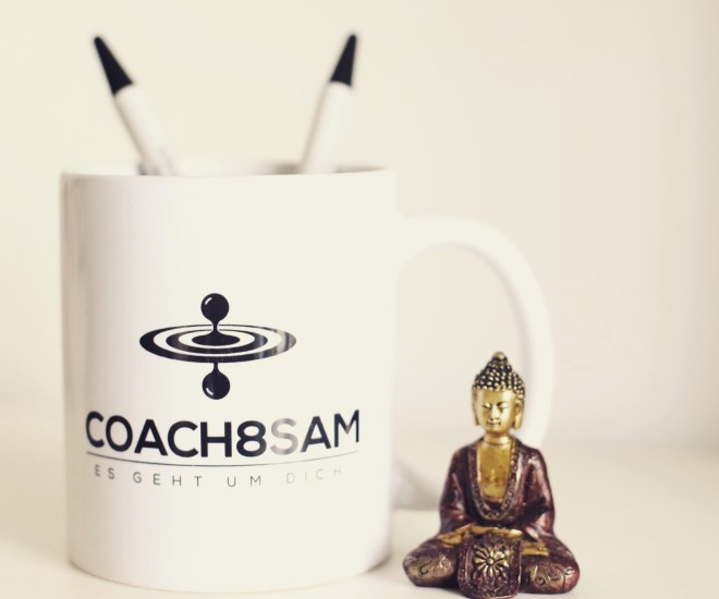 Tasse mit Aufschrift Coach8Sam und kleinem sitzenden Buddha daneben